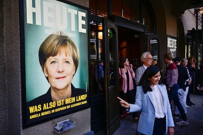Una mujer posa frente al cartel que anuncia la primera intervención pública de Angela Merkel en el teatro Berliner Ensemble.