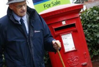 Un hombre pasea cerca de un buz&oacute;n de correos de Royal Mail.