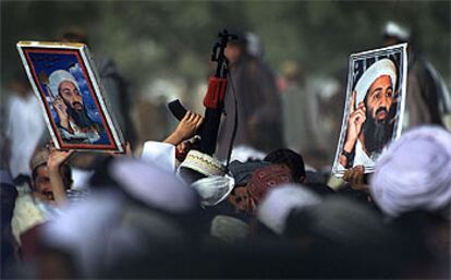 Dos carteles con el busto de Bin Laden y  un fusil de juguete aparecen por encima de las cabezas de unos manifestantes en Pakistán a favor de los talibanes en 2001.