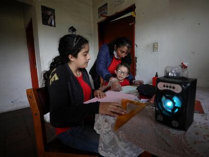 Fanny Méndez, a la derecha, madre de Marlene Beltrán, de 14 años, a la izquierda, y Felipe Beltrán, de cinco, ayuda a sus hijos en casa a hacer un cubo de papel mientras escuchan una lección de una hora transmitida por la radio Bacata Stereo, en mayo de 2020.