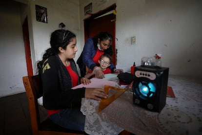 Fanny Méndez, a la derecha, madre de Marlene Beltrán, de 14 años, a la izquierda, y Felipe Beltrán, de cinco, ayuda a sus hijos en casa a hacer un cubo de papel mientras escuchan una lección de una hora transmitida por la radio Bacata Stereo, en mayo de 2020.