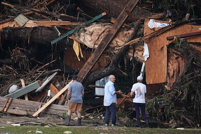 Varias personas miran los daños causados tras las inundaciones por la crecida del río Guadalupe en Hunt, este sábado.