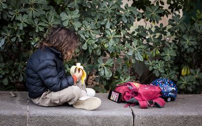 Un niño de primaria mira el móvil mientras desayuna en un parque de Barcelona.