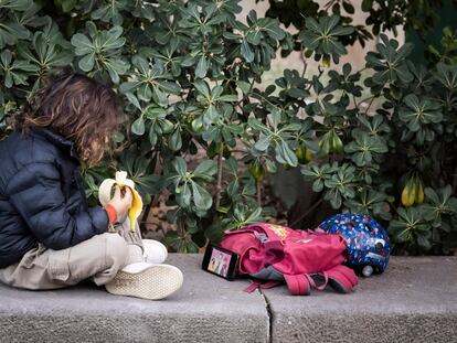 Un niño de primaria mira el móvil durante la merienda en un parque de Barcelona.