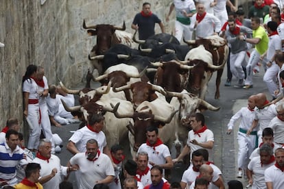 Los mozos corren delante de los toros de la ganadería salmantina de Puerto de San Lorenzo en la cuesta de Santo Domingo, durante el tercer encierro de los Sanfermines 2017.