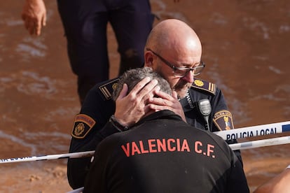 Un miembro de la policía local abraza a un hombre tras conocerse que un compañero murió en las inundaciones que han afectado a Valencia, este jueves. 