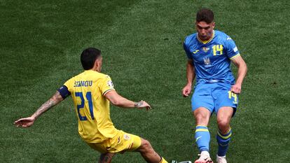 El rumano Nicolae Stanciu pelea el balón con Sudakov de Ucrania.