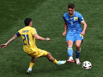 El rumano Nicolae Stanciu pelea el balón con Sudakov de Ucrania.