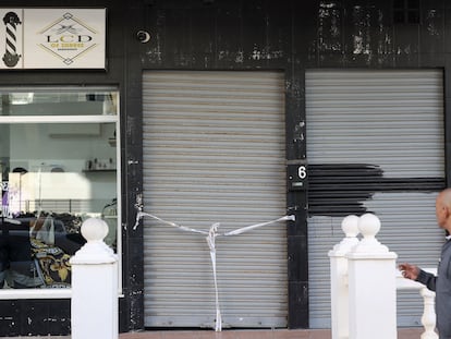 Una persona camina frente a un local precintado por la Policía Nacional en la zona de la localidad de Fuengirola donde han matado a tiros a un hombre.