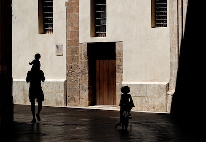 A man walks outside with his two children in Valencia.