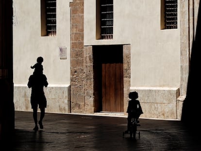 A man walks outside with his two children in Valencia.