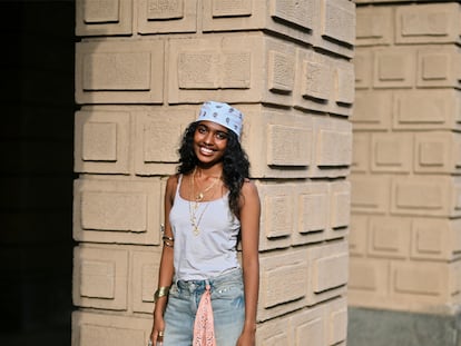 Una chica con bandana en la cabeza y otra enganchada en el pantalón posando para una foto.