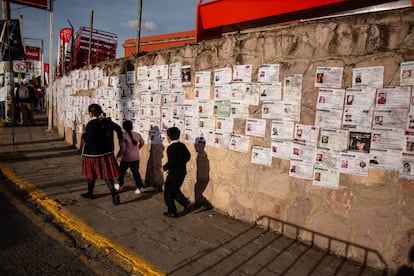 Tres niños pasan frente a un muro cubierto de fichas de búsqueda de personas desaparecidas, en Zacatecas, en septiembre pasado.