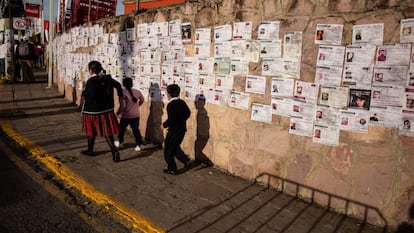 Tres niños pasan frente a un muro cubierto de fichas de búsqueda de personas desaparecidas, en Zacatecas, en septiembre pasado.