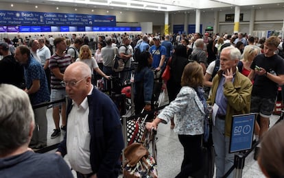 Personas hacen cola junto a sus pertenencias para facturar con la compañía British Airways en el aeropuerto de Gatwick, Reino Unido.