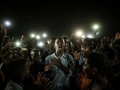 Un joven, iluminado por teléfonos móviles, recita un poema mientras los manifestantes cantan consignas pidiendo un gobierno civil, durante un apagón en Jartum (Sudán), el 19 de junio de 2019.