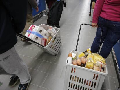 Varias personas haciendo la compra en un supermercado.