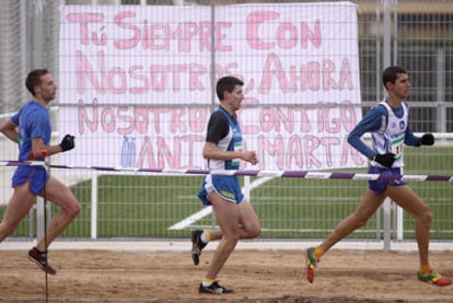 Tres atletas corren frente a una pancarta en apoyo de Marta Domínguez.