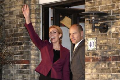 La nueva primera ministra danesa Helle Thorning-Schmidt saluda a sus seguidores ante la puerta de su casa en Copenhague junto con su marido, Stephen Kinnock.