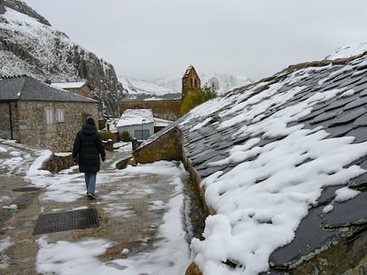 Una mujer camina por las calles de La Cueta, en León, donde el paisaje está cubierto de nieve.