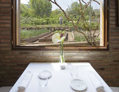 Una de las mesas del restaurante Venta Moncalvillo, en Daroca de Rioja, con la huerta de la que se abastece al fondo. 