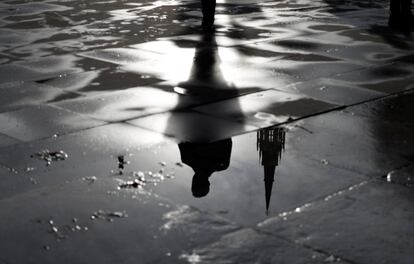 El Palacio de Westminster y un hombre caminando se reflejan en un charco en Londres (Gran Bretaña).