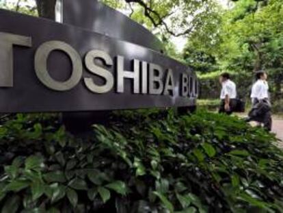 Dos hombres caminan frente a la sede de la empresa japonesa de electrónica Toshiba en Tokio, Japón. EFE/Archivo
