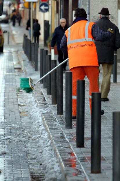 Un barrendero limpia esta mañana a primera hora la acera de la Rambla de Justo Oliveras en l'Hospitalet de Llobregat.