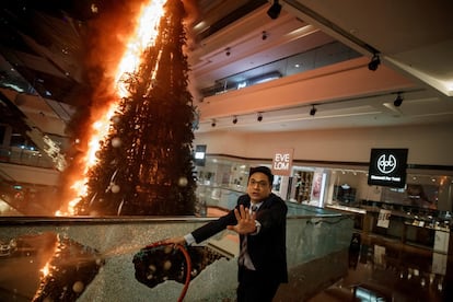 Un trabajador de seguridad pide precaución mientras arde un árbol de Navidad en el centro comercial en Kowloon Tong en Hong Kong, el 12 de noviembre de 2019.