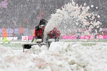 Un operario retira la nieve del campo de juego antes del partido de fútbol de la Bundesliga alemana entre FC Cologne y SC Freiburg en Colonia, Alemania.