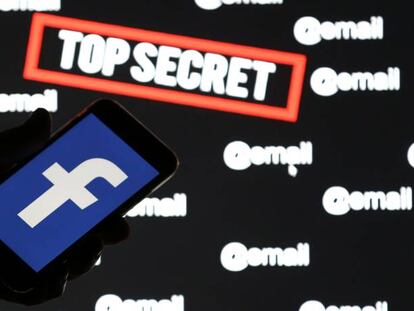 Una persona sostiene un móvil con el logo de Facebook sobre una pantalla con las palabras 'top secret' e '@email'.