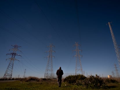 Un hombre pasea cerca de torres de tendido eléctrico a las afueras de Sevilla.