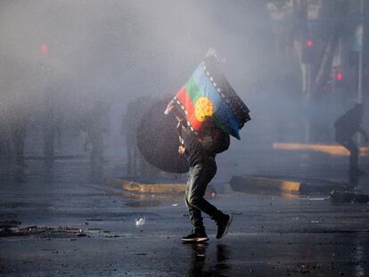 Un hombre se protege de un cañón de agua durante una protesta en 2022.