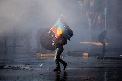 Un hombre se protege de un cañón de agua durante una protesta en 2022.
