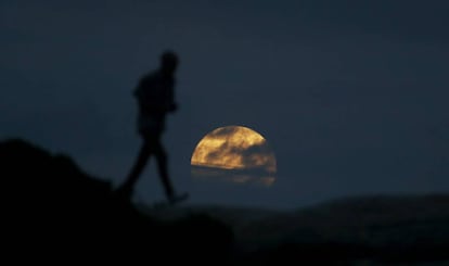 Una mujer observa la luna cerca de la playa Bondi en Sídney (Australia).