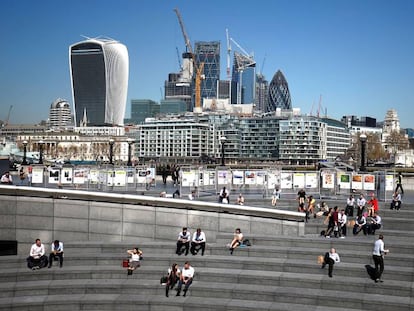 Londinenses relajándose al sol cerca del Ayuntamiento, con la City al fondo.