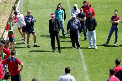 Los <i>ultras,</i> con Fran, el del traje, y Portu, con gorra, al frente insultando a los jugadores ante la mirada reprobatoria de Bastn, cruzado de brazos.