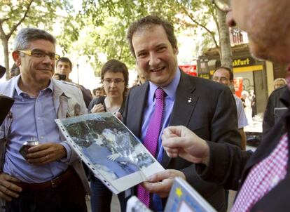 Un vecino muestra a Jordi Hereu, una fotografía del expresidente del Gobierno, José María Aznar, y del candidato a la Alcaldía de la ciudad condal por CiU, Xavier Trias.