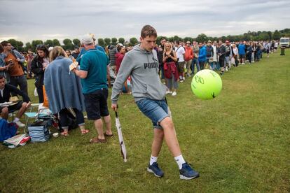 Un joven da patadas a una pelota gigante de tenis mientras espera a que se abra al público el All England Tennis Club donde se celebra el torneo de Wimbledon.