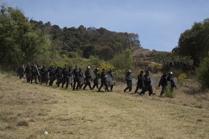 Un grupo de granaderos de la policía estatal se retira de los terrenos en disputa.