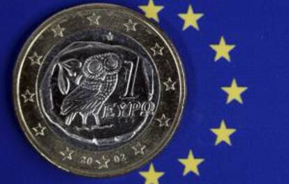 Una moneda de euro griego permanece sobre el emblema de la Unión Europea, en un despacho de Schwerin, Alemania. EFE/Archivo