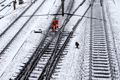 Un operario limpia las vías del tren de hielo y nieve, en Ginebra (Suiza).