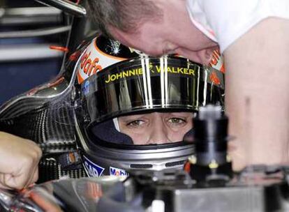 Fernando Alonso contempla cómo un mecánico de McLaren-Mercedes realiza los últimos ajustes a su coche antes de los entrenamientos oficiales de este sábado en Melbourne.