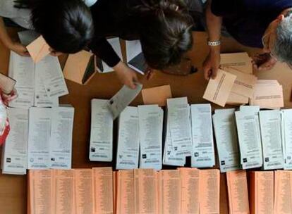 Varios electores cogen ayer papeletas en un colegio electoral.