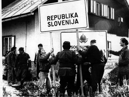 Milicianos eslovenos colocan un cartel de la República de Eslovenia en el puesto fronterizo de Jerzersko-Seebergsattel, en su poder, después de que soldados del Ejército yugoslavo lo abandonaran en 1991.