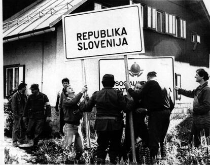 Milicianos eslovenos colocan un cartel de la República de Eslovenia en el puesto fronterizo de Jerzersko-Seebergsattel, en su poder, después de que soldados del Ejército yugoslavo lo abandonaran en 1991.
