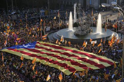 A large estelada flag is carried by protesters in Plaza de Cibeles.