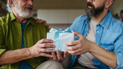 Un hijo dándole un regalo con una caja de rayas azul a su padre.