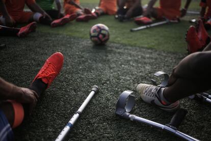 Los jugadores de fútbol de "Las muletas" descansan sobre el cesped del estadio Deir Al Balah, tras una sesión de entrenamiento.
