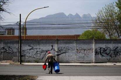 Un hombre carga una cubeta y un bote de basura para almacenar agua y transportarla, en la ciudad norteña de Monterrey.